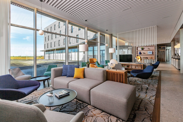 The comfortable lounge area with sofas, chairs, and television at the Courtyard by Marriott Reykjavik Keflavik Airport.