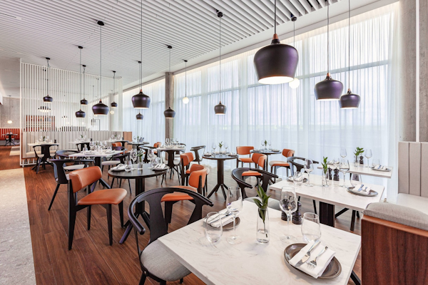 Tables are set with cutlery and glasses in the dining room at the Courtyard by Marriott Reykjavik Keflavik Airport.