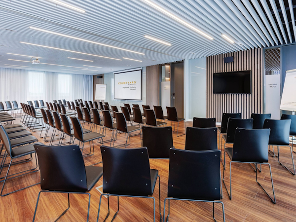 A large event room lined with chairs at the Courtyard by Marriott Reykjavik Keflavik Airport.