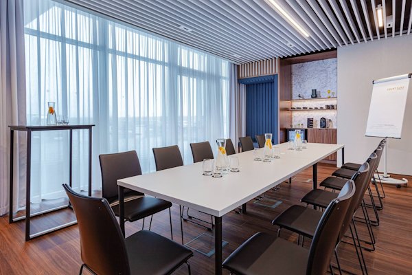 A large table and chairs in a meeting room at the Courtyard by Marriott Reykjavik Keflavik Airport.