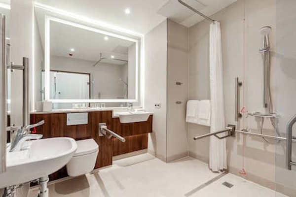 An accessible bathroom with a roll-in shower and grab rails at the Courtyard by Marriott Reykjavik Keflavik Airport.