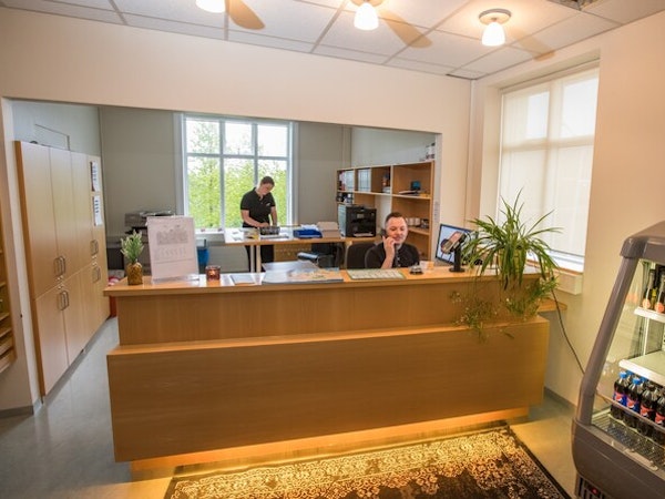Two people are on the phones in the Hotel Laugar Reykjadalur reception area.