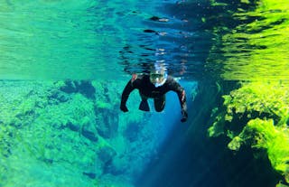 A person snorkels through the Silfra fissure in Iceland.
