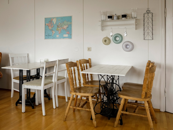 The dining area at Dalvik HI Hostel with tables, chairs, shelving, and a world map on the wall.
