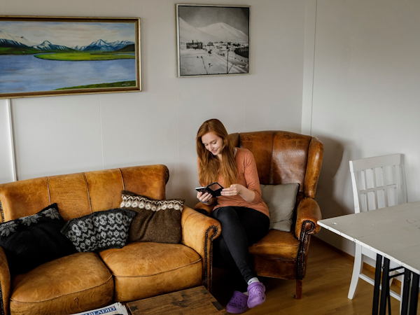 A lady relaxes on a comfortable chair in the shared lounge area at Dalvik HI Hostel.