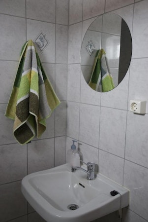 A bathroom with a basin, mirror, and hand towel at Grundarfjordur HI Hostel.