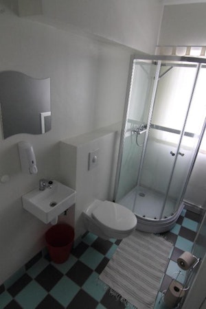 A bathroom with a toilet, shower, mirror, and basin at Grundarfjordur HI Hostel.