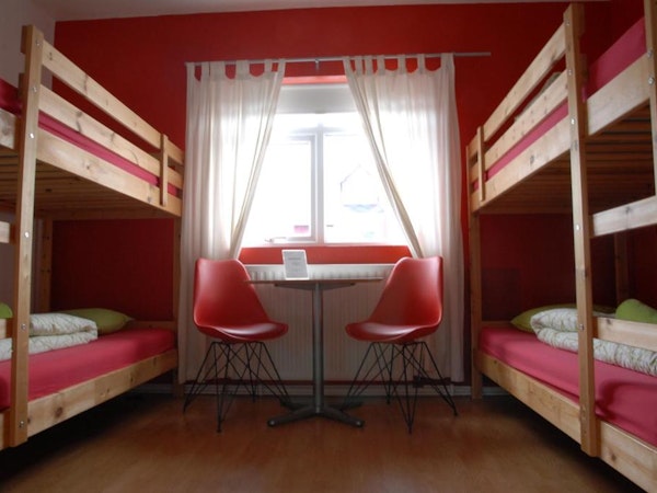 Two bunk beds in a room at Grundarfjordur HI Hostel with a table and chairs between.
