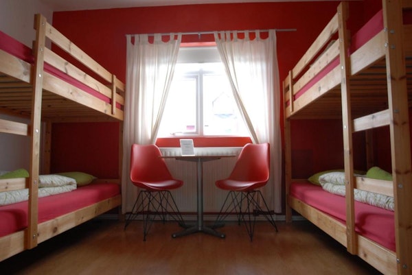 Two bunk beds in a room at Grundarfjordur HI Hostel with a table and chairs between.