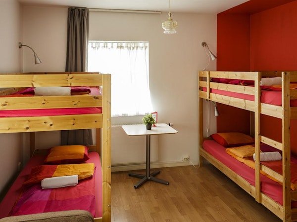 Two bunk beds in a room at Grundarfjordur HI Hostel with bedding, towels, lamps, and a table.