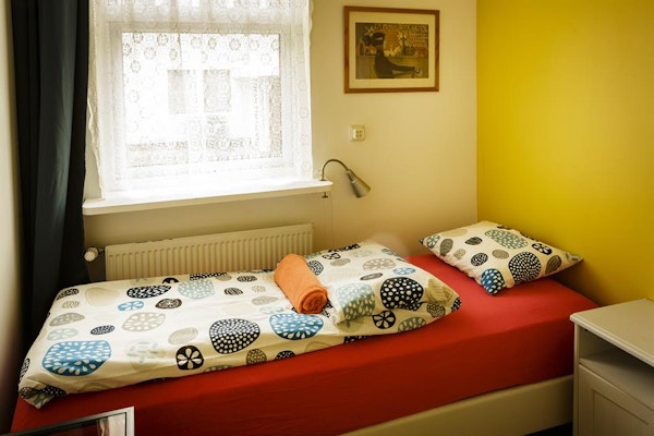 A single room at Grundarfjordur HI Hostel with a bed, bedding, towel, and artwork on the wall.