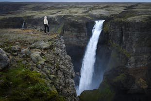 A person poses on an overlook at the Haifoss waterfall, one of the tallest in Iceland.
