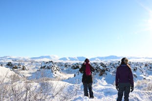นักท่องเที่ยวยืนมองภูมิประเทศแบบภูเขาไฟของทะเลสาบมิวาทน์ที่มีหิมะปกคลุมขาวโพลนในช่วงหน้าหนาว