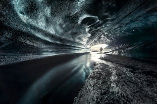 A person is silhouetted from light streaming in the entrance of the ice cave at Katla Volcano.