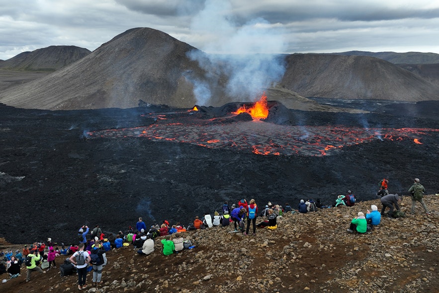 游客在Meradalir山谷欣赏从火山裂缝中喷出的岩浆