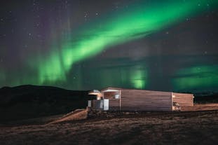 The Black Beach Suites on Iceland's South Coast underneath the vibrant northern lights.