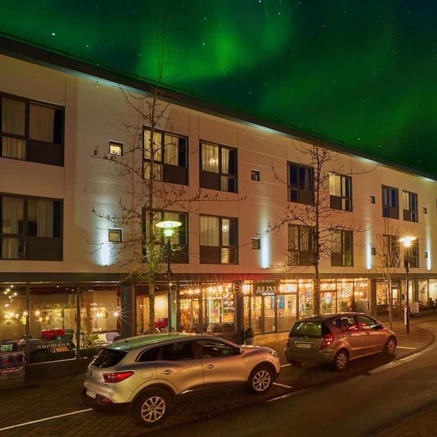 Top 10 hotels in Reykjavik-Alda hotel exterior with the northern lights shining in the sky above.