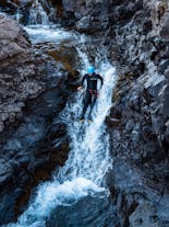 A person uses a waterfall as a slide on this thrilling canyoning tour in Southeast Iceland.