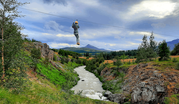 A person zip lines over the river on the Akureyri zipline tour.
