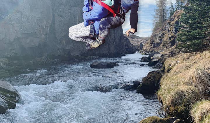 Two women zipline together over a river in Iceland.