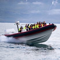 A group of tourists enjoying a whale-watching tour onboard a RIB in North Iceland.