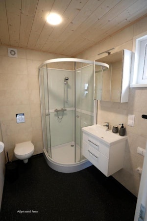 A modern bathroom with a shower, basin, toilet, and soap at Eyri Seaside Houses in Northwest Iceland.