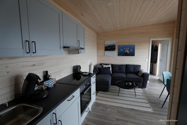 An open plan kitchen and living area with an l-shaped sofa at Eyri Seaside Houses in Northwest Iceland.