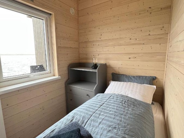 A modern single room with towels, linen, and bedside drawers at Eyri Seaside Houses in Northwest Iceland.