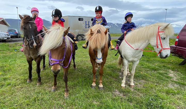 Children happily mount their horses in preparation for their horseback riding tour.