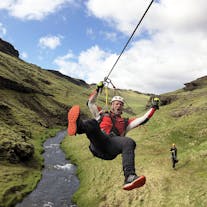 A participant on this exciting ziplining tour zooms across a river.