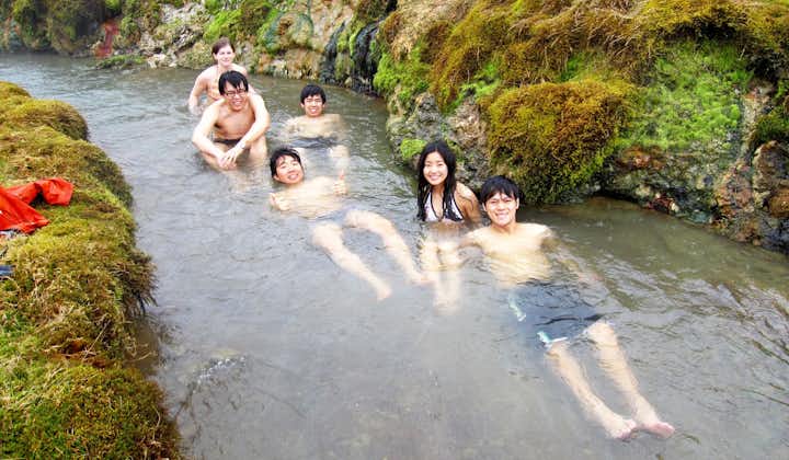 A small group of tourists enjoy bathing in the geothermal river in Reykjadalur Valley.