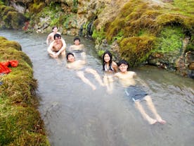 A small group of tourists enjoy bathing in the geothermal river in Reykjadalur Valley.
