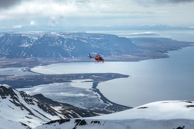 A helicopter takes skiers to their mountaintop destination.