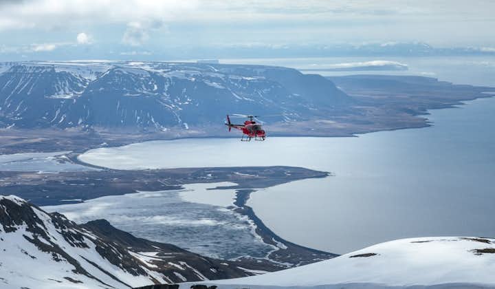 A helicopter flying back over the mountains in North Iceland.
