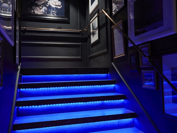 The stairway at Hotel Akureyri Dynheimar in central Akureyri lit up in bright blue, with framed pictures on the walls.