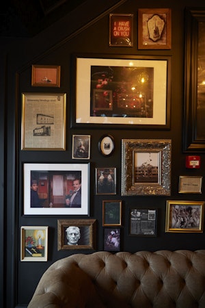A close-up view of various framed artwork, pictures, and newspaper clippings, and a sofa in the hallway at Hotel Akureyri Dynhei