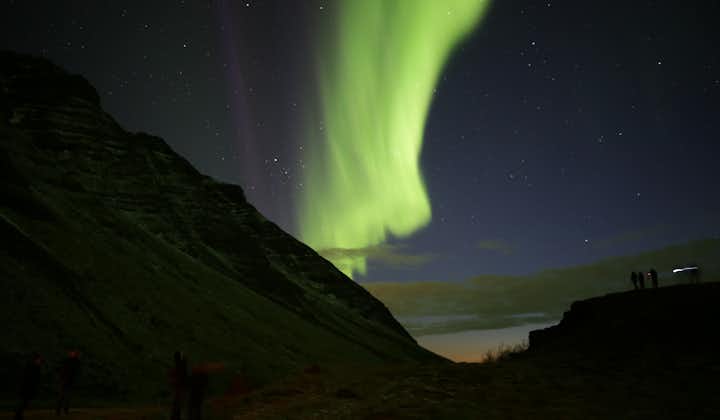 The aurora borealis lights up the starry night sky in a brilliant splash of green, a winter bucket list adventure for many travelers to Iceland.