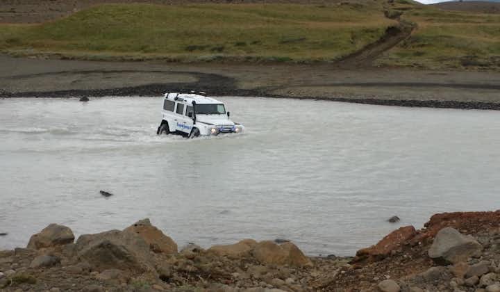 A modified super jeep drives through a river, tackling terrain off-limits to most vehicles.
