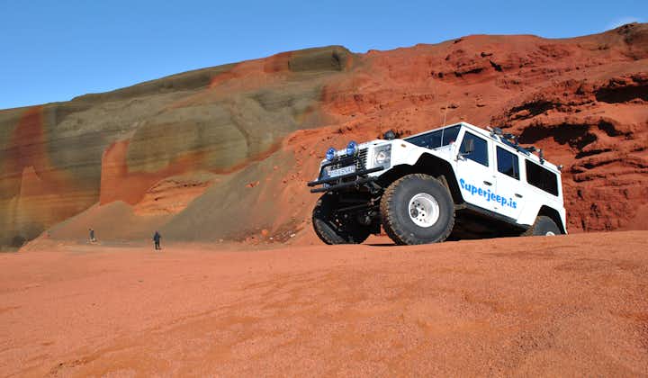 A large Super Jeep parked on the red slopes of a volcanic crater in Iceland.
