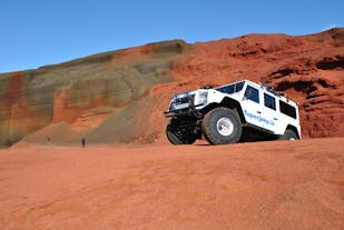A large Super Jeep parked on the red slopes of a volcanic crater in Iceland.