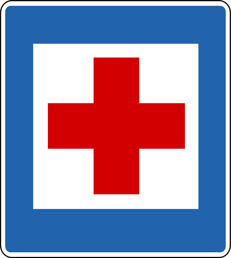 A square sign with a white background, blue border, and red cross in the middle shows indicates a nearby first aid station.