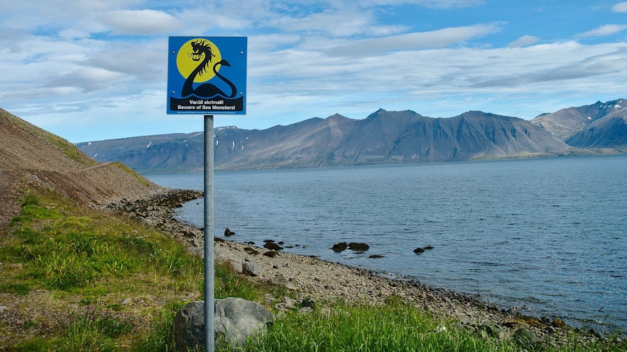 A lakeside sign in Iceland warning people to be careful of sea monsters.