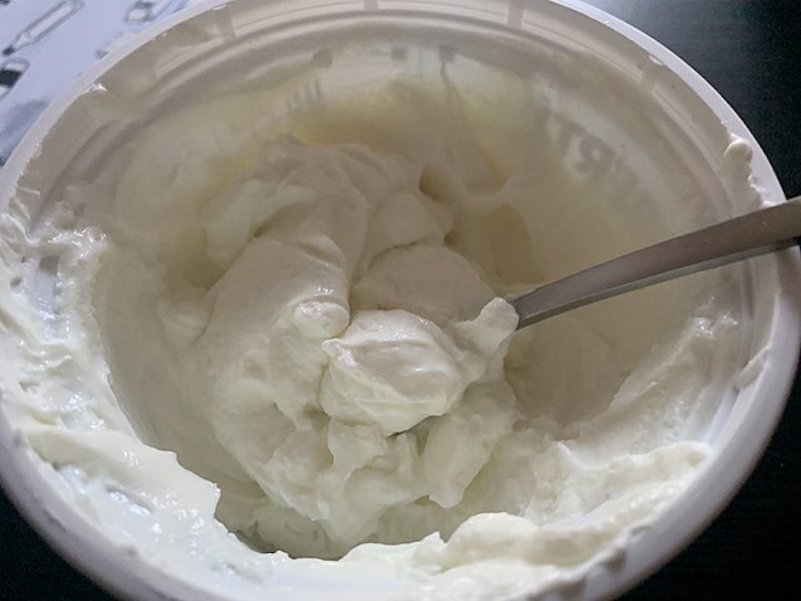 Skyr bought from the grocery store with a silver-colored spoon inside the tub.