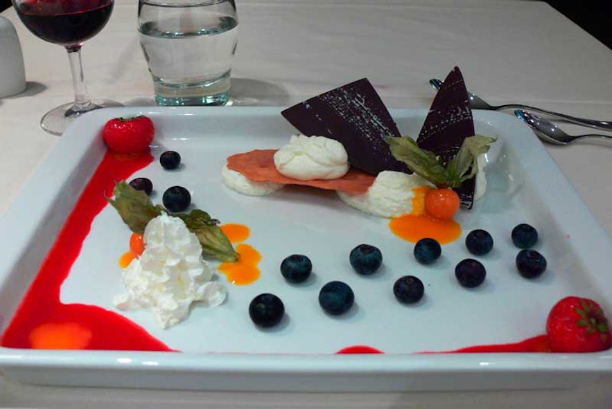 A dessert of skyr with blueberries, fresh fruit, and whipped cream served in a restaurant.