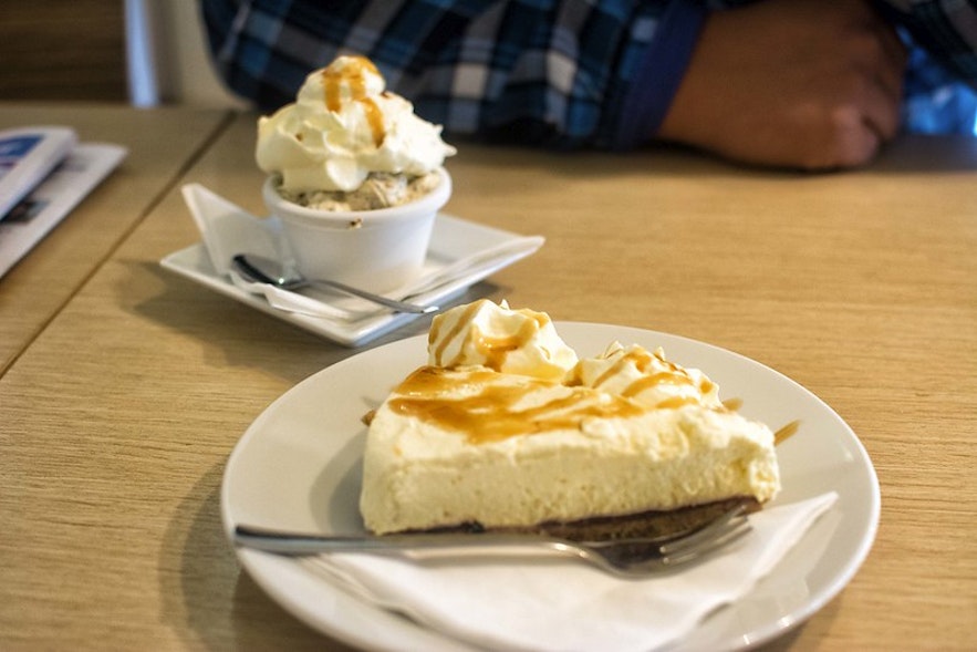 A cheesecake topped with skyr and served with a drizzle of caramel and whipped cream.