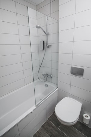 A bathroom in Bella Hotel, Selfoss, featuring a shower above a bath.