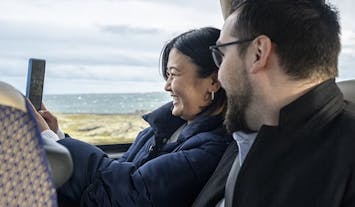 Woman and man are seen sitting in a bus smiling.