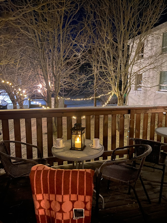 A gorgeous outdoor seating area with a table, chairs, blanket, and lights in the trees at Dala Hotel.