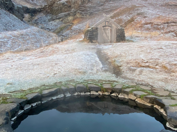 The Gudrunarlaug hot spring and hut near Dala Hotel with picturesque countryside surroundings.