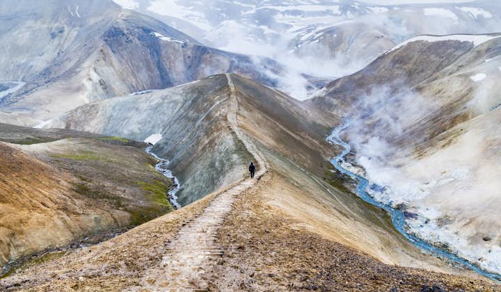 A person walking along a mountain-top trail in Landmannalaugar, famous for its hiking routes.